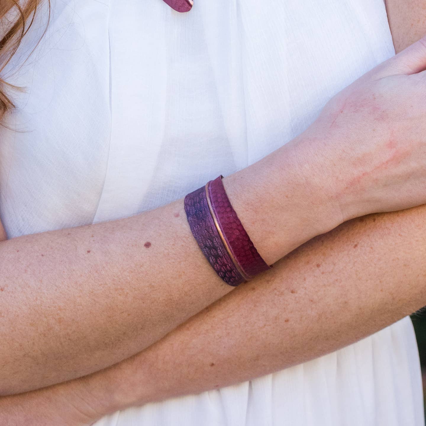 Stylish Copper Patina Bracelet with Red Feathers and Circular Designs